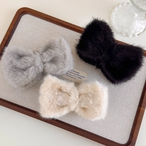 Barrettes à cheveux élégantes en peluche grise, noire et beige sur un plateau en bois