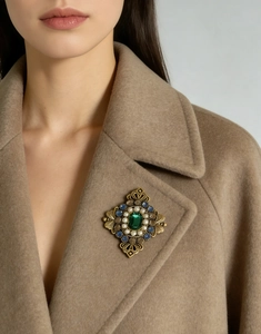 Spilla vintage con smeraldo e perle sul risvolto di un cappotto di lana color cammello