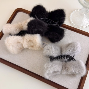 Détail de quatre pinces à cheveux en peluche avec nœuds en noir, beige et gris clair