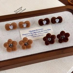 Brown flocked bow and flower stud earring set with rhinestones on a wooden jewelry tray
