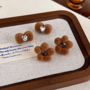 Detail of coffee flocked bow and flower stud earrings with zircon on wooden tray