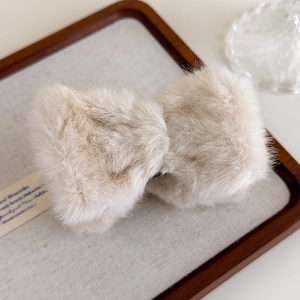 Gros plan sur la pince à cheveux nœud en fausse fourrure beige à texture pelucheuse