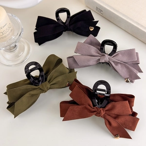 Detail showing four colors of large velvet bow hair claws with gold heart charm