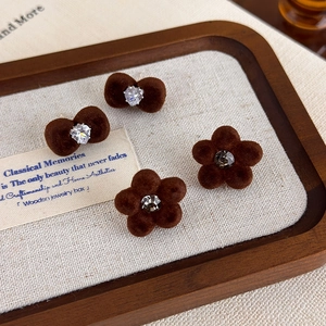 Close-up of velvet brown bow and flower stud earrings with sparkling rhinestones detail