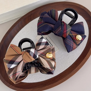 Elegant British plaid bow hair clips in navy and brown on a vintage wooden tray
