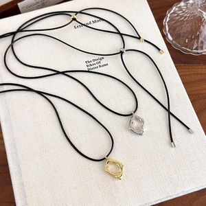 Collier avec pendentif goutte géométrique minimaliste en or et argent posé sur un livre