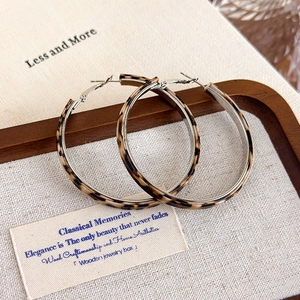 Macro view of leopard print hoop earrings with silver metal inner band on linen