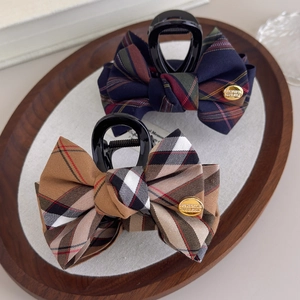 Classic British style plaid bow claw clips in beige and navy on a wooden tray