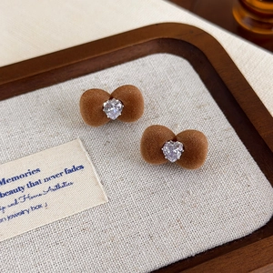 Detailed view of brown flocked bow earrings with a heart-shaped crystal center