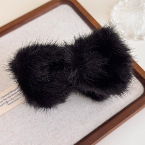 Gros plan de pinces à cheveux en peluche noire sur un plateau en bois avec détails