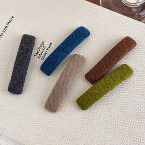 Detailed view of five colorful knitted fabric barrette clips on a vintage book background