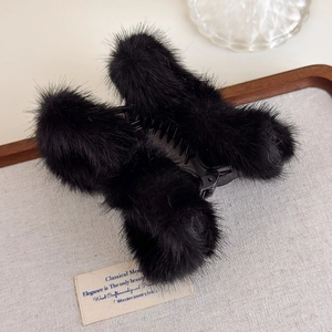 Détail de la pince à cheveux en peluche noire élégante avec texture douce en gros plan