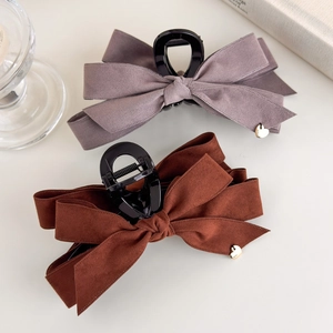 Detail of large velvet bow hair claws featuring golden heart charms and black resin teeth