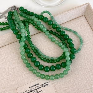Vue macro de colliers de perles de jade vert superposés avec fermoir mousqueton en métal