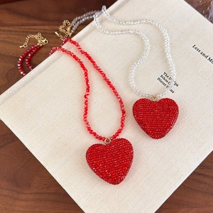 Colliers avec pendentifs cœur en cristal rouge et perles sur une surface de livre