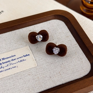 Close-up of brown flocked bow earrings with a sparkling heart-shaped zircon center