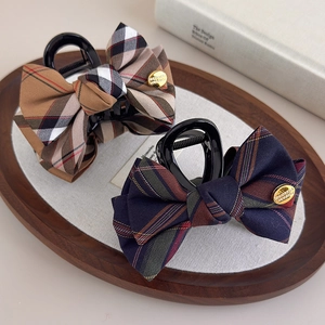 Detail of British style plaid bow hair claw clip with engraved golden metal button