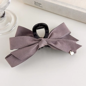Detail of purple velvet bow hair claw clip with a delicate gold heart pendant
