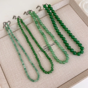 Détail de quatre colliers de perles en pierre naturelle verte aux nuances variées avec fermoir