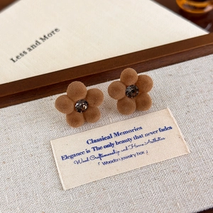 Macro shot of brown flocked flower earrings with dark grey crystal on a canvas background
