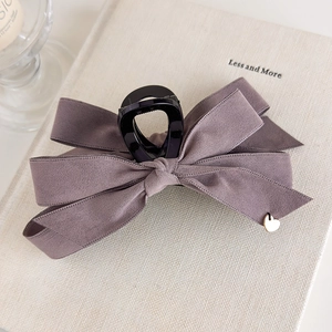 Detailed macro of a lavender velvet bow hair claw clip with a golden heart charm