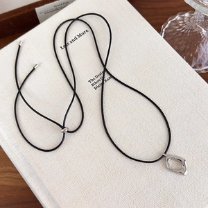 Détail du pendentif argenté creux sur cordon noir posé sur un livre ancien de style rétro