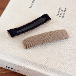Detail of light brown knitted fabric texture and black metal hair clip base on a book