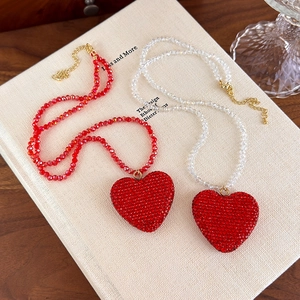 Détail de colliers cœur rouge avec pendentifs en cristal sur chaîne de perles