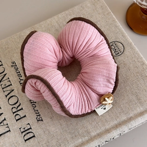 Dettaglio scrunchie in maglia rosa con etichetta fatta a mano e decoro a stella marina