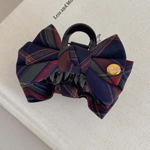Detail of British style plaid fabric bow hair claw clip with golden metal decorative button
