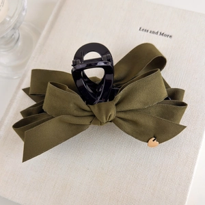 Detail view of large velvet bow hair claw clip with a golden heart charm in olive green