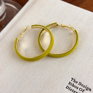 Gros plan de grandes boucles d'oreilles créoles vintage en velours jaune moutarde et or