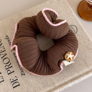 Dettaglio macro dell'elastico per capelli rosa e marrone con stella marina e etichetta