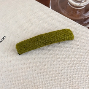Detailed close-up of a moss green rectangular plush hair clip with a soft velvet texture