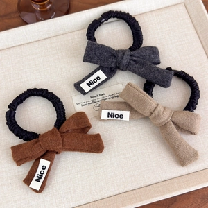 Three-piece set of knitted bow scrunchies in grey, brown, and tan with Nice label