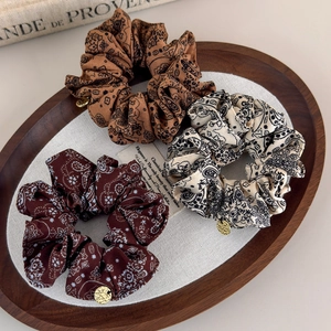 Detailed close-up of paisley pattern hair scrunchies with decorative gold metal charms