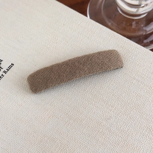 Close-up of brown plush hair clip on book page showing soft knitted texture
