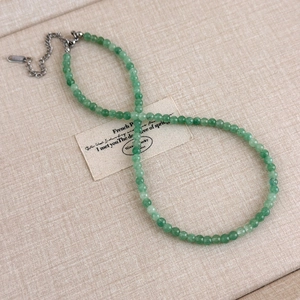 Détail de perles de pierre vert émeraude facettées sur un collier avec chaîne en métal