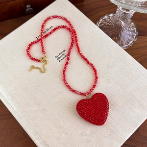 Détail du collier pendentif coeur en cristal rouge avec perles rouges sur un livre