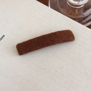 Detail view of a rectangular dark brown plush hair clip with a soft matte velvet texture
