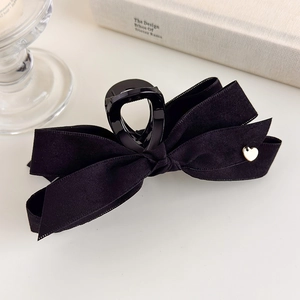 Close-up of elegant black velvet bow hair claw with a small golden heart metal detail