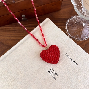 Détail d'un collier pendentif coeur en cristal rouge avec sa chaîne en perles rouges