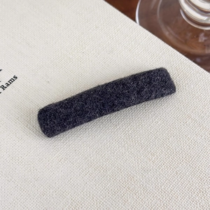 Close-up of black plush rectangle hair clip showing soft felt texture and metal base