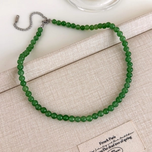 Détail du collier de perles vertes avec fermoir mousqueton argenté sur support en tissu