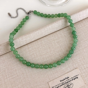 Détail d'un collier de perles vert émeraude avec fermoir et chaîne en argent
