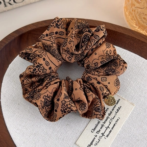 Close-up of vintage paisley print scrunchie with ornate golden metal pendant detail