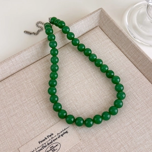 Détail du collier de perles vert émeraude avec fermoir mousqueton en argent sur plateau