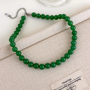 Détail des perles vert foncé et du fermoir en argent sur un présentoir à bijoux