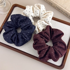 Set of three polka dot fabric scrunchies in white navy and red on a vintage tray