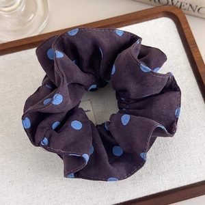 Close-up of retro large purple velvet scrunchie with blue polka dots on a tray